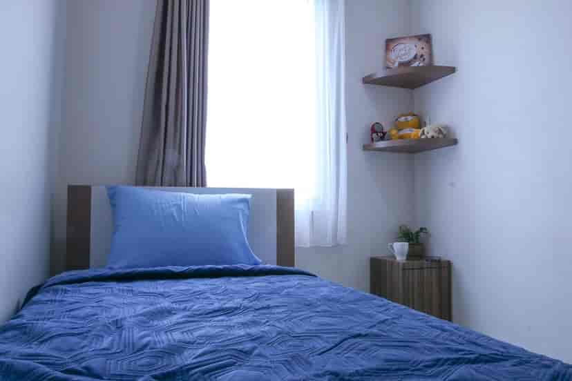 A bedroom with a single bed, nightstand and simple decor.