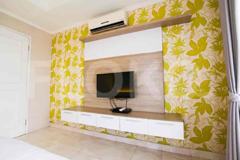 A bedroom with a wall-mounted TV and patterned wall.