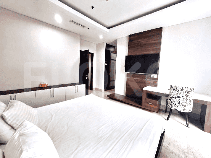 A bedroom featuring a large bed, TV, and desk space.