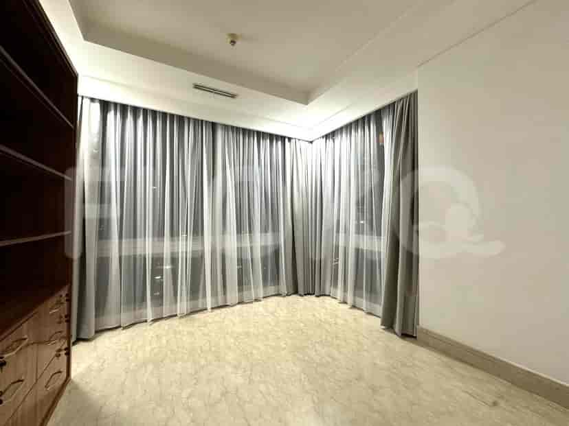 A bedroom with a large window with sheer curtains.