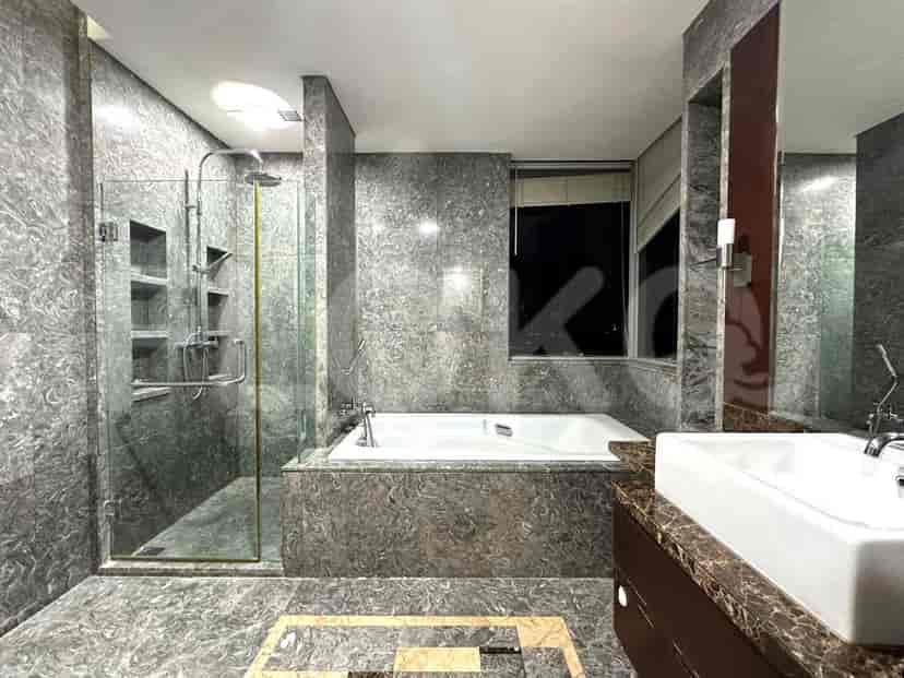 Kamar mandi dengan bak mandi, pancuran, dan dinding marmer.