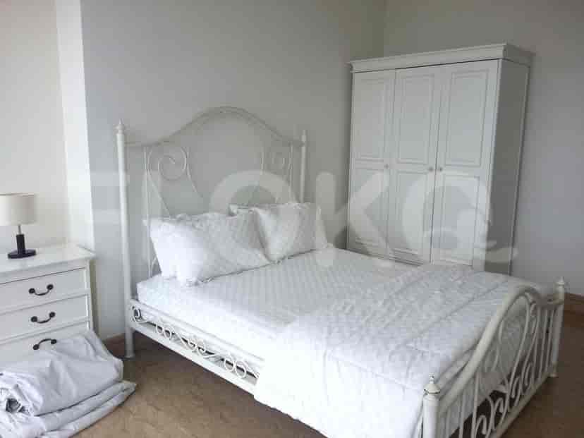 A bedroom with a white bed frame, a white wardrobe, and a white nightstand.
