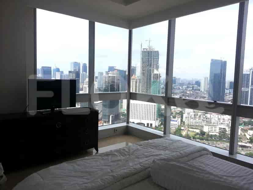 A bedroom with a city view from a large window.