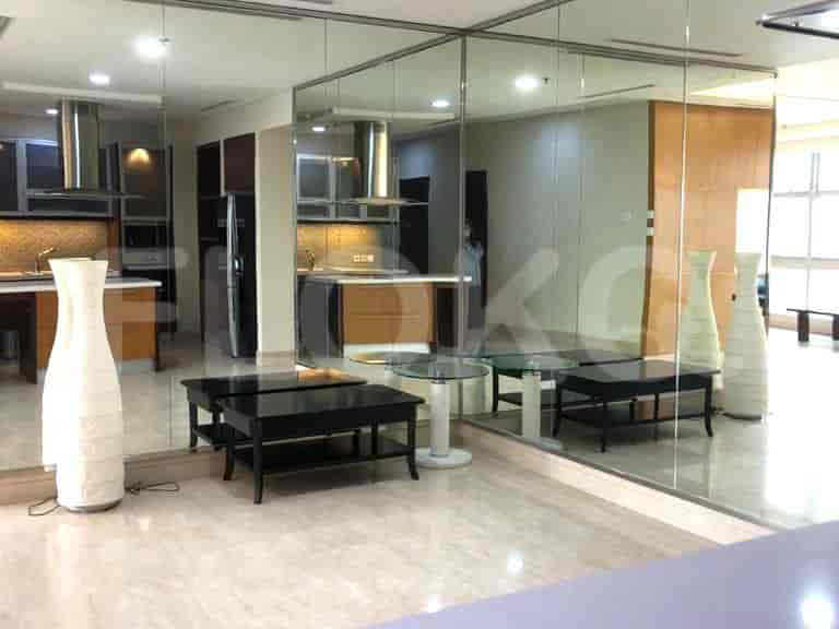 Living area with mirrors, black coffee tables, and a view of the kitchen.