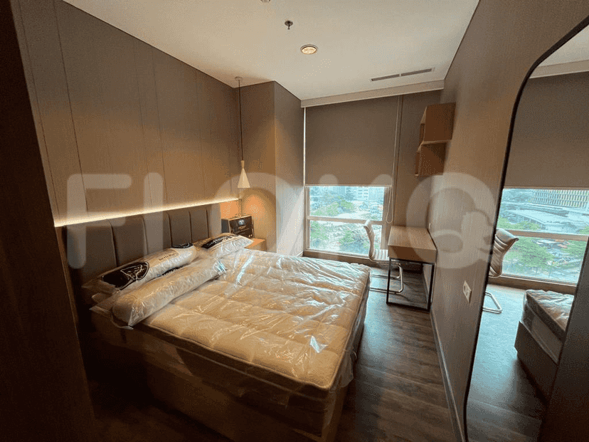 A well-lit bedroom with a bed, a desk, and a large window.