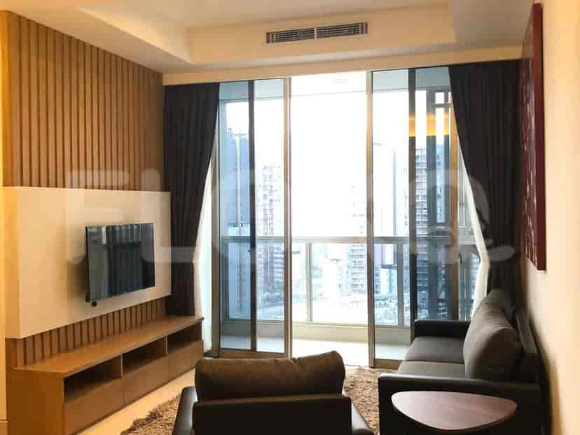 Living room with a sofa, wall-mounted TV, and large windows with a city view.