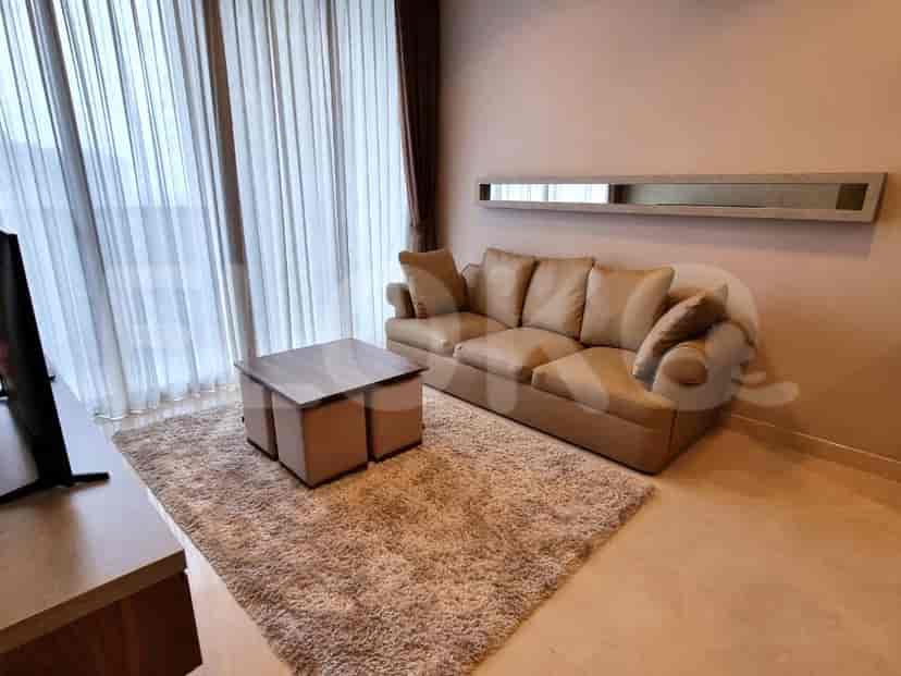 A living room with a beige sofa, coffee table, and large window with curtains.