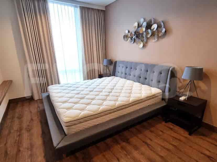 A bedroom with a grey bed, side tables, and wall art.