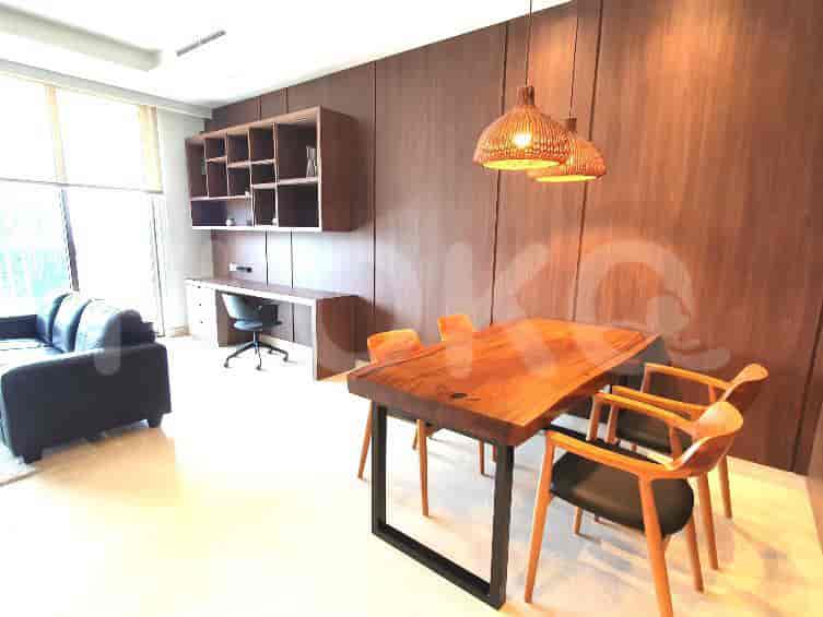 Modern living space with dining area, built-in shelving, and black leather sofa.