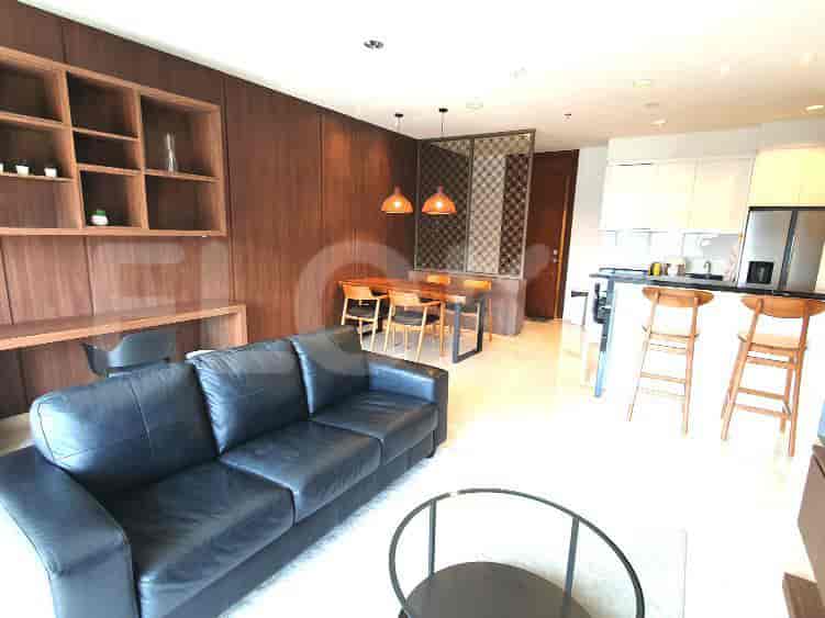 Modern living space with a black leather sofa, dining table, and open kitchen.