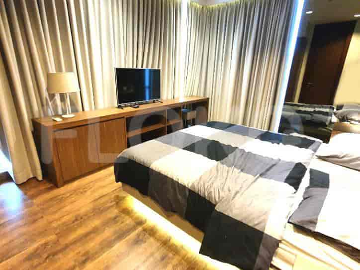 Modern bedroom with a large bed, TV, and curtains.