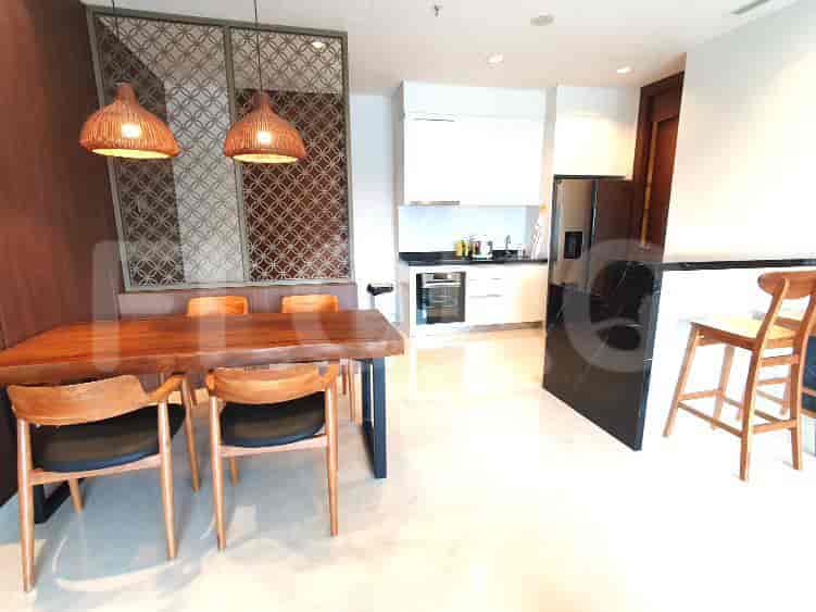 Modern living space with a dining area, open kitchen, and black leather sofa.