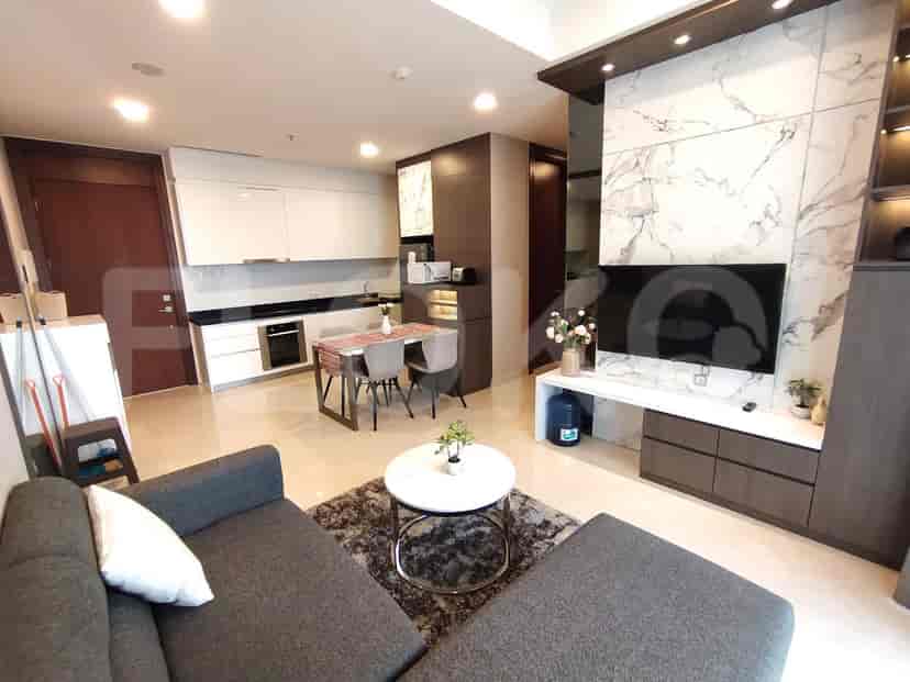 Open-plan living space with a modern kitchen, dining area, and living room with a grey sofa and TV.