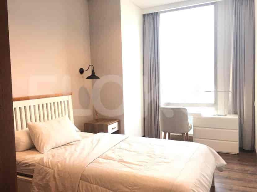 A cozy bedroom with a bed, bedside table, and a large window with city view.