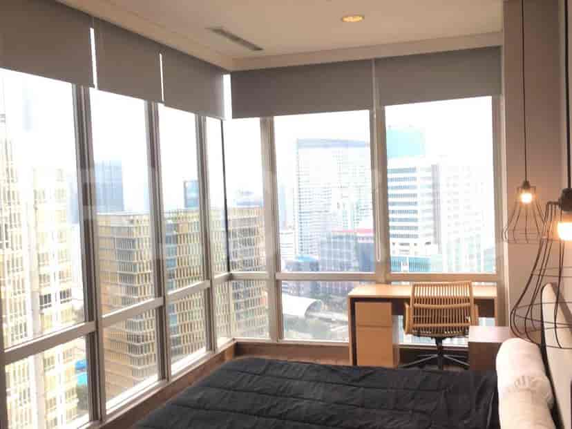 A bedroom with floor-to-ceiling windows offering expansive city views.