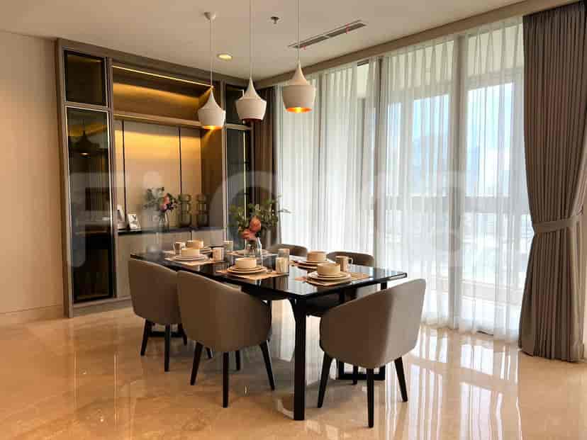 A dining area with a table, chairs and large windows with curtains.