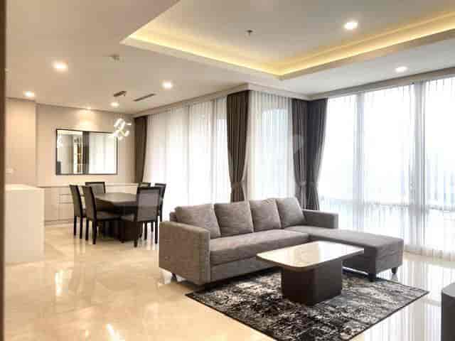 A combined living and dining space, featuring a grey sofa, dining table and a city view.