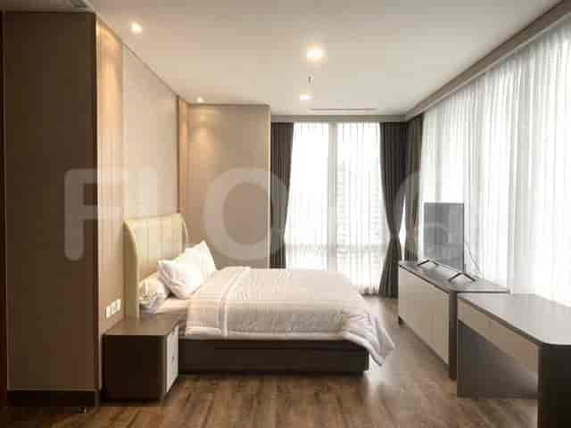 A bedroom with a king-sized bed, TV and a desk.