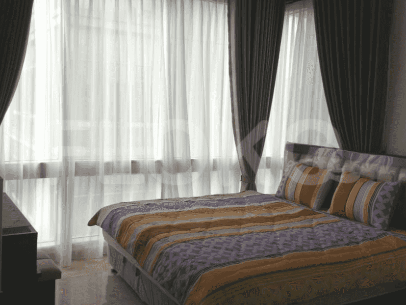 A bedroom featuring a bed with colorful bedding and sheer curtains.