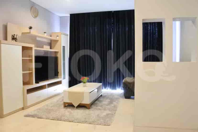 Modern living room with a sofa, smart TV, and large windows.