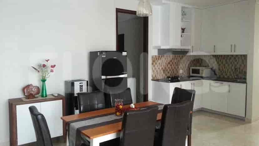 A kitchen with white cabinets, a dining table with black leather chairs, and a refrigerator.