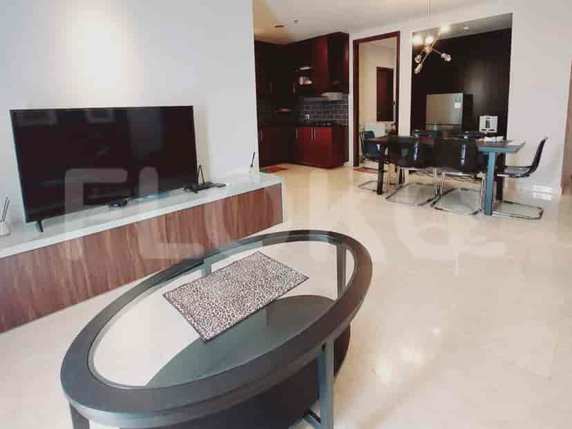 Living room with a large TV, coffee table, and open kitchen view.