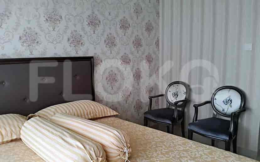 A bedroom with floral wallpaper, a double bed, and two armchairs.