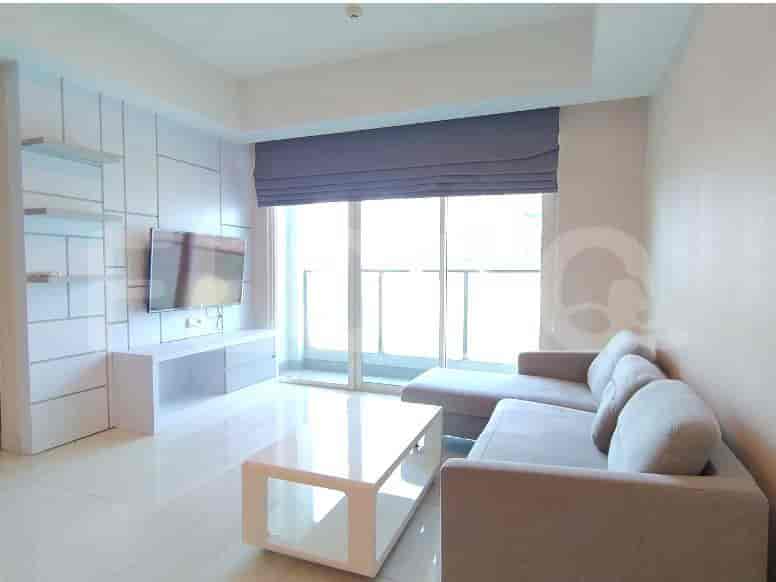 Modern living room with a sectional sofa, wall-mounted TV, and large windows.