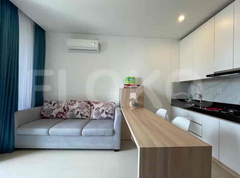 Ruang gabungan ruang tamu dan dapur dengan sofa, meja makan, dan lemari dapur putih.