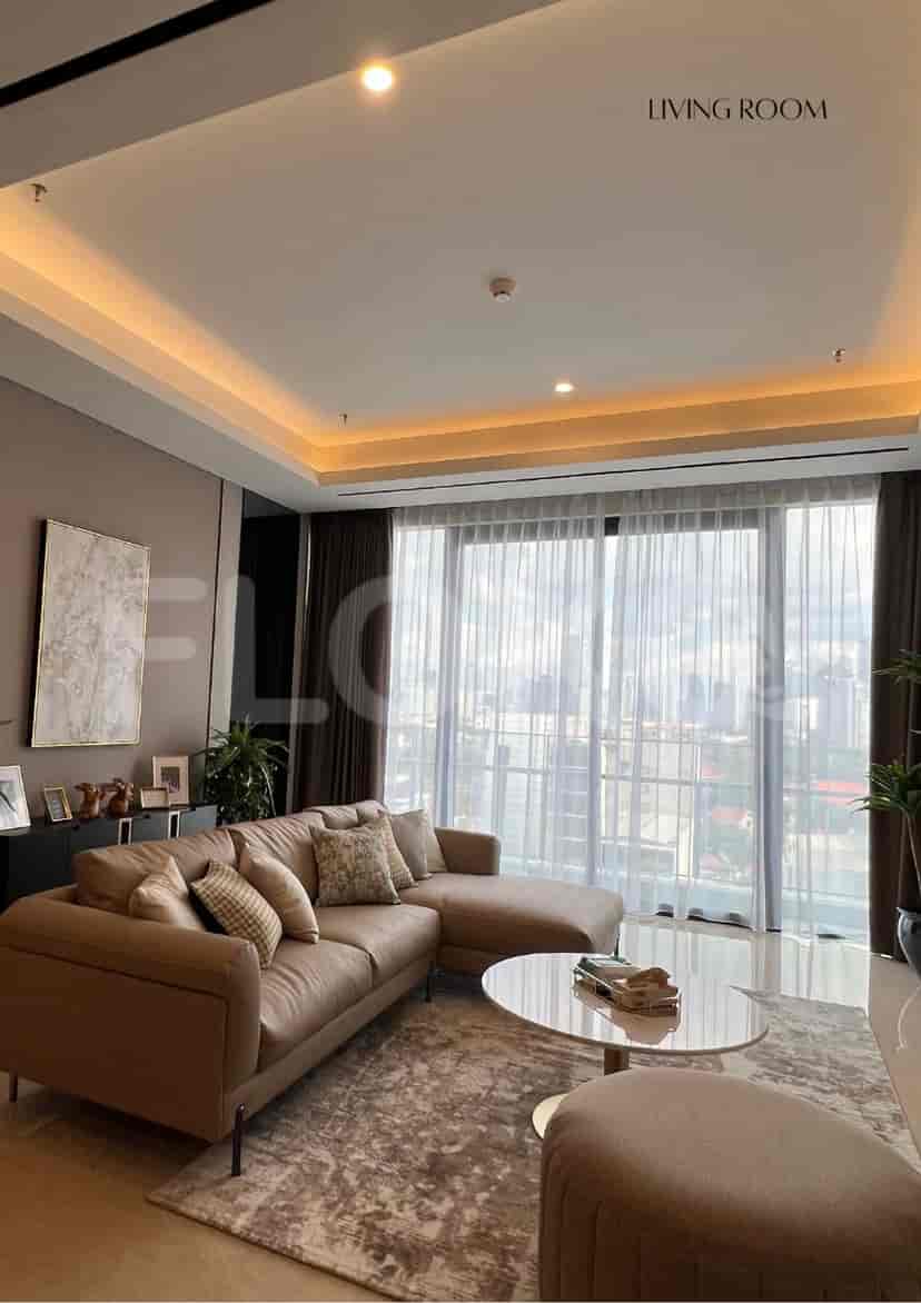 Ruang tamu dengan sofa berbentuk sectional, TV pintar, dan jendela besar yang menawarkan pemandangan kota.