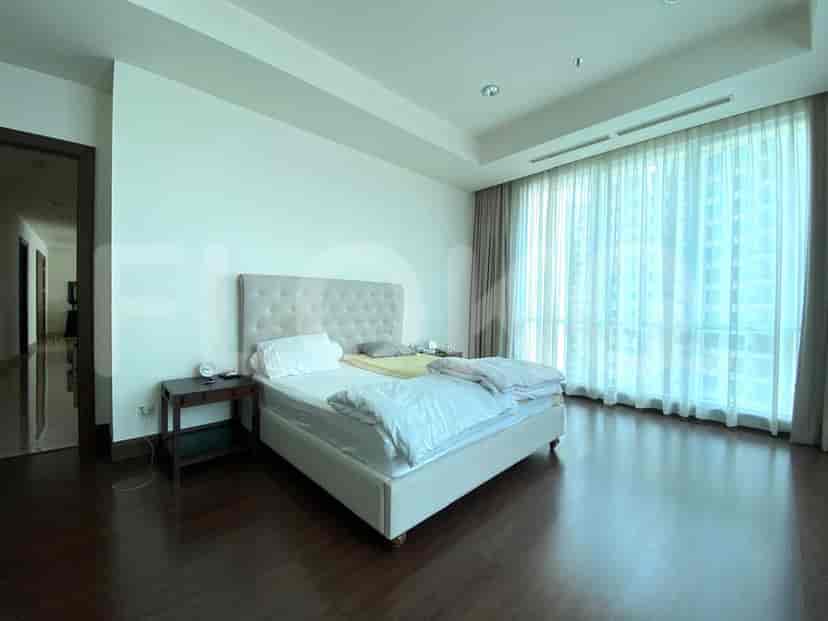 Spacious bedroom with a queen-sized bed and large windows with curtains.