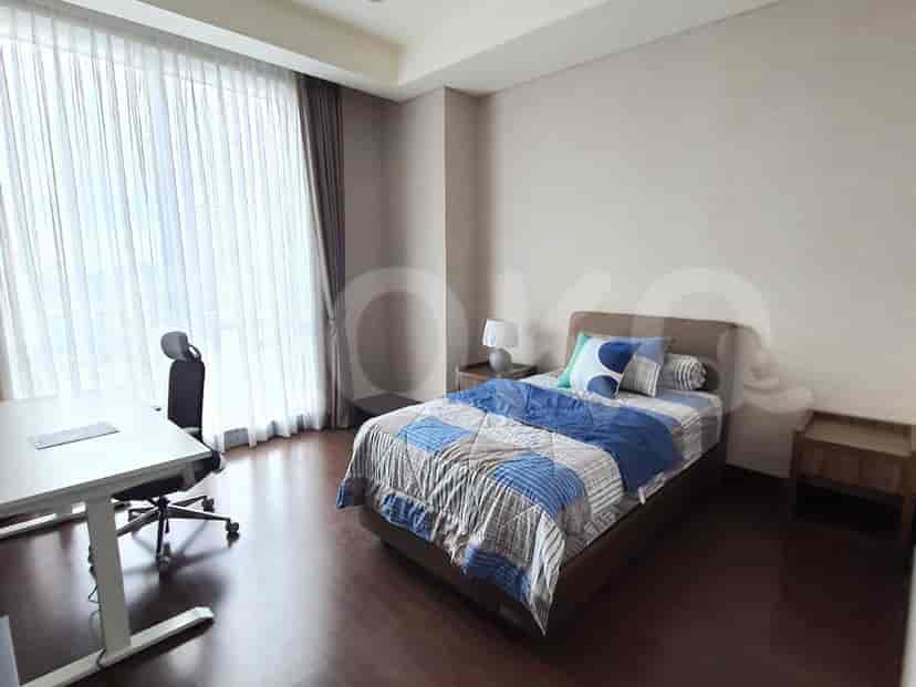 A bedroom with a single bed, a desk, and large windows.