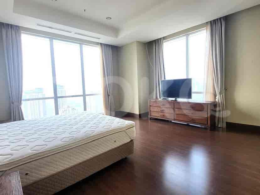 Spacious bedroom with large windows offering a city view, a king-size bed, and a wooden dresser.