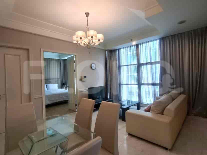 A bright living room with a view of a bedroom through the open door and a dining area to the left.