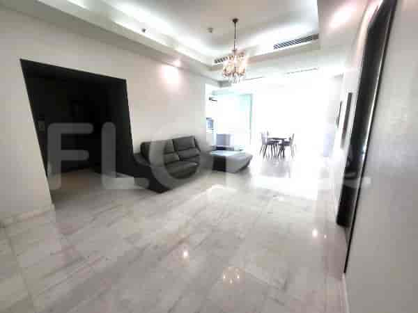 Entryway with a view into the living room. It features marble floors, a grey sofa, and a chandelier.
