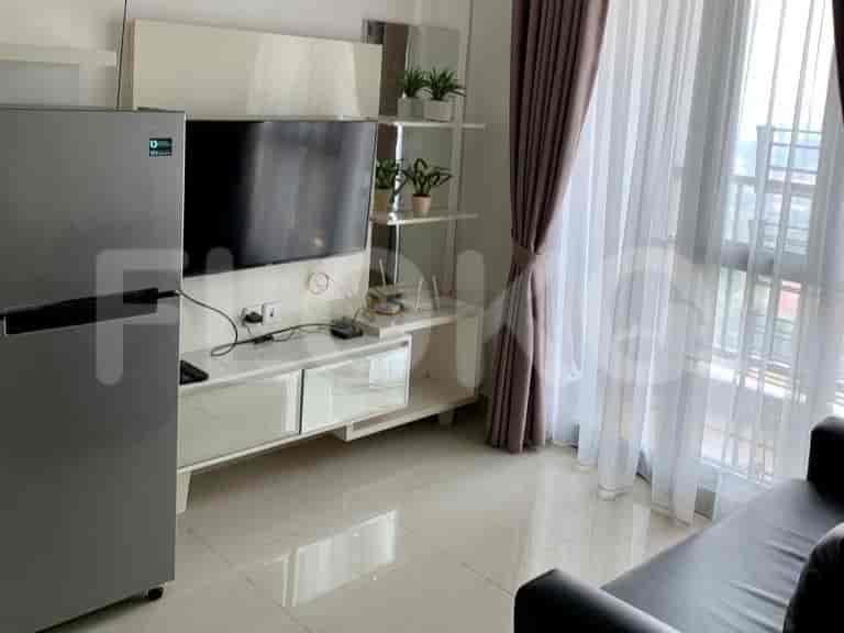A living room with a TV, shelves, and a view from the window.
