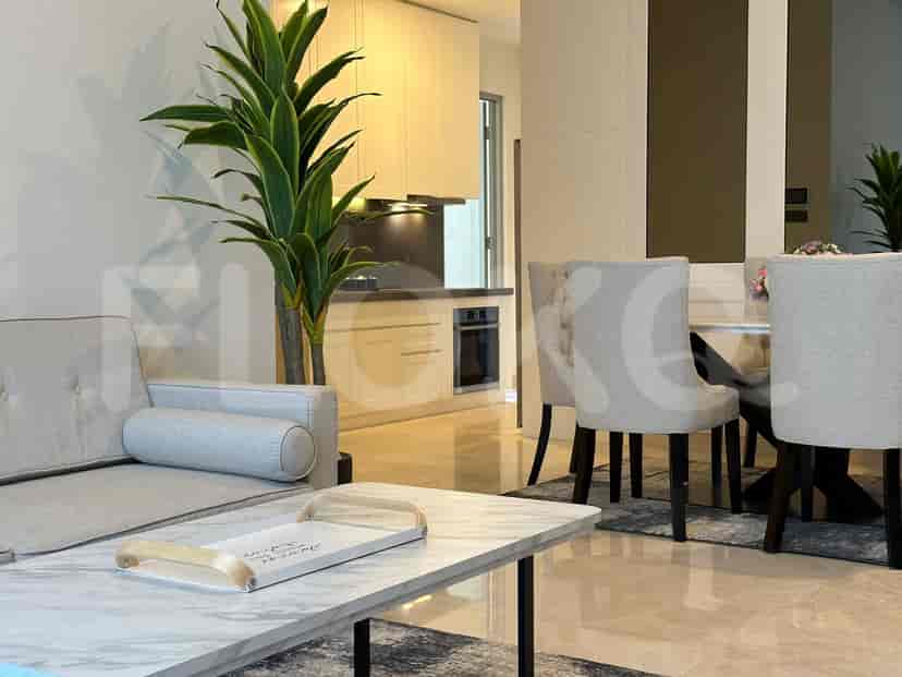 A modern living room with a grey sofa, marble coffee table, and an open kitchen in the background.