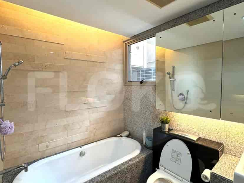 Kamar mandi modern dengan bak mandi dan cermin besar.