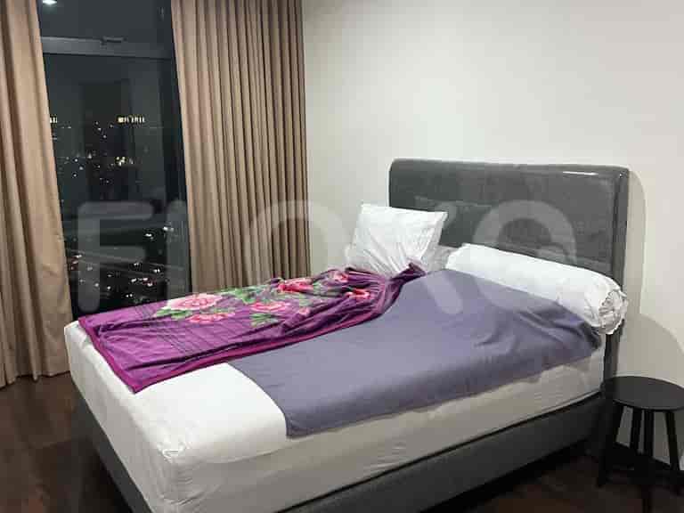 A cozy bedroom featuring a double bed with a floral blanket, neutral tones, and large windows.