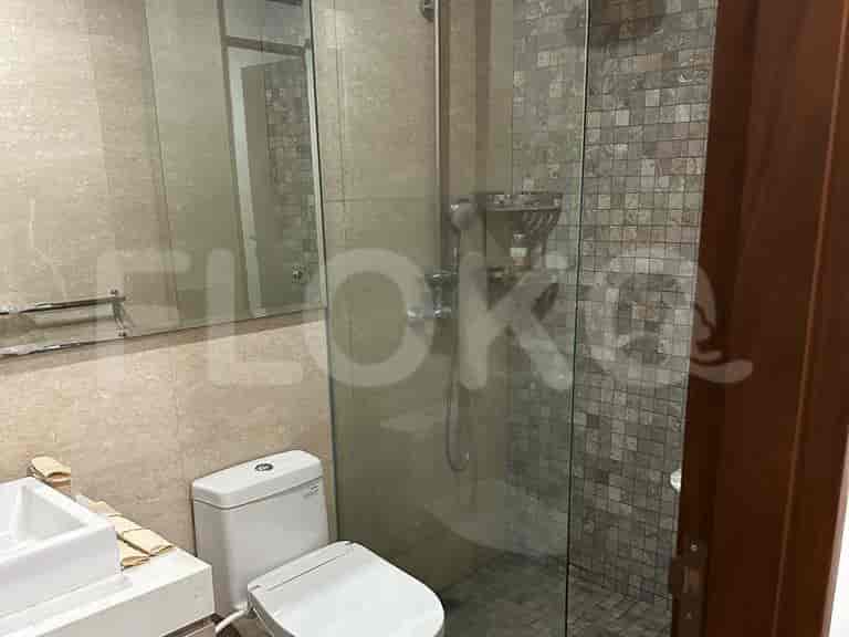 A modern bathroom with a glass-enclosed shower, neutral tile, and a mounted mirror.