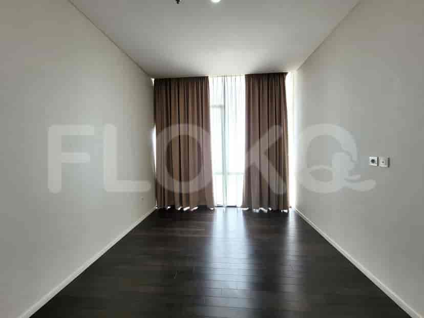 An empty room with dark flooring and large windows.