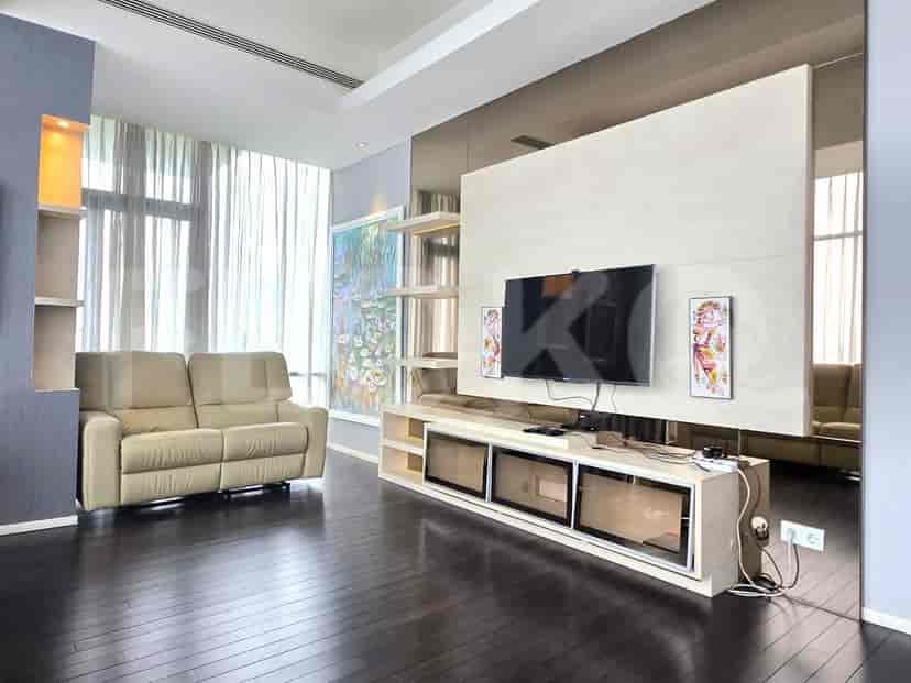 Living room with a large tv, sofa and dark wooden floor.