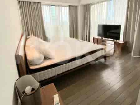 A bedroom featuring a bed, window curtains, and a wooden side table.