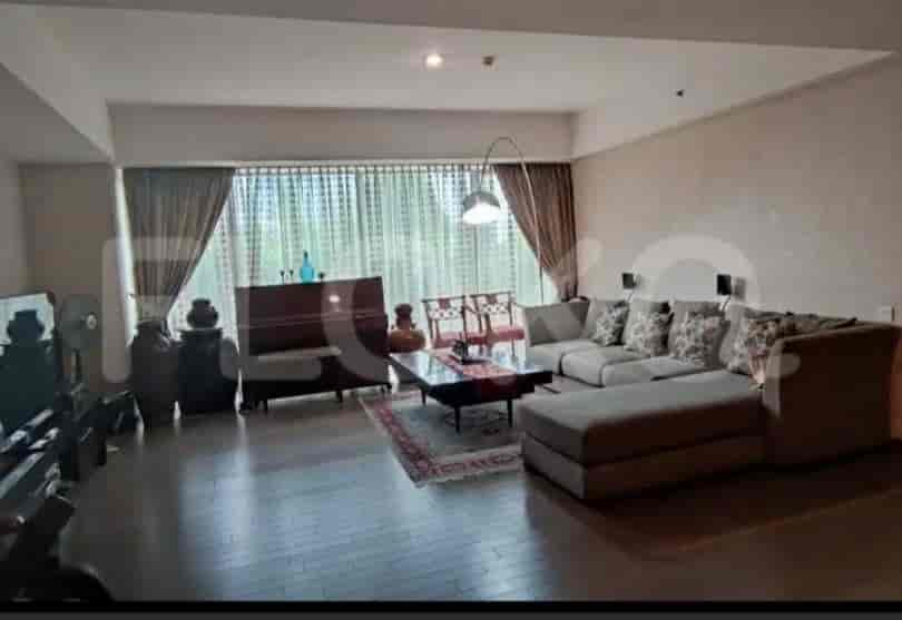 A spacious living room with an L-shaped grey sofa, large window, and wooden flooring.