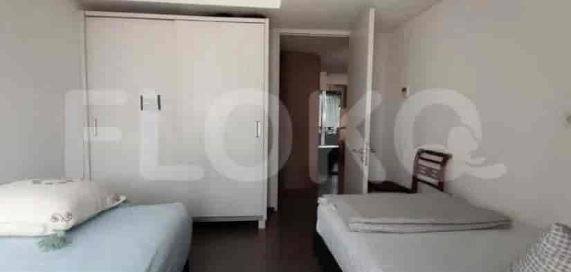 A small bedroom with two beds, a wardrobe, and access to a bathroom.