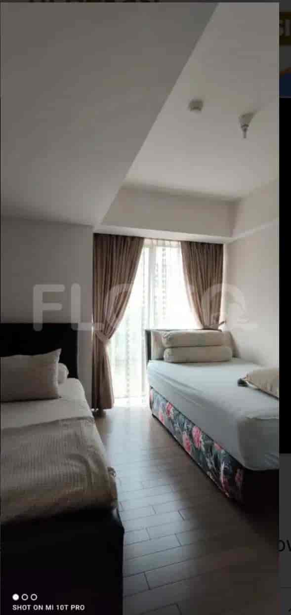 A bedroom with two beds, window, and curtains.