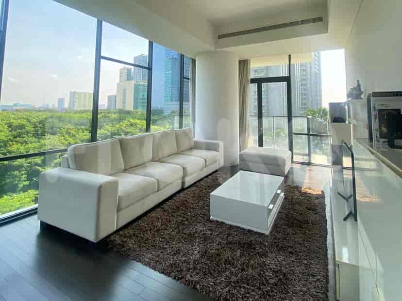 A bright living room with a white sofa, large windows, and a coffee table.
