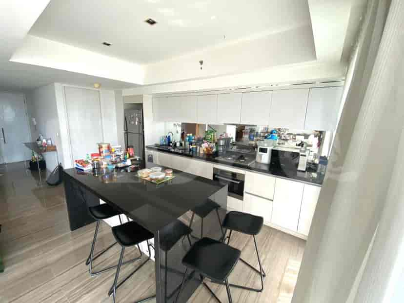 A modern kitchen with a black island, white cabinets, and stainless steel appliances.