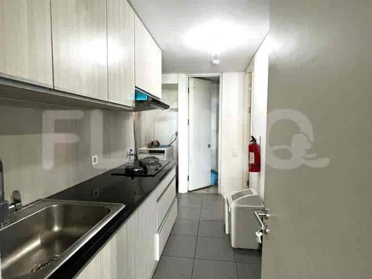 A compact kitchen with cabinetry, appliances, and a view into the hallway.