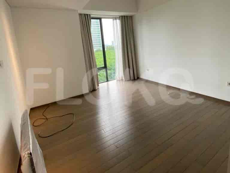 Empty room with wooden flooring and a large window.